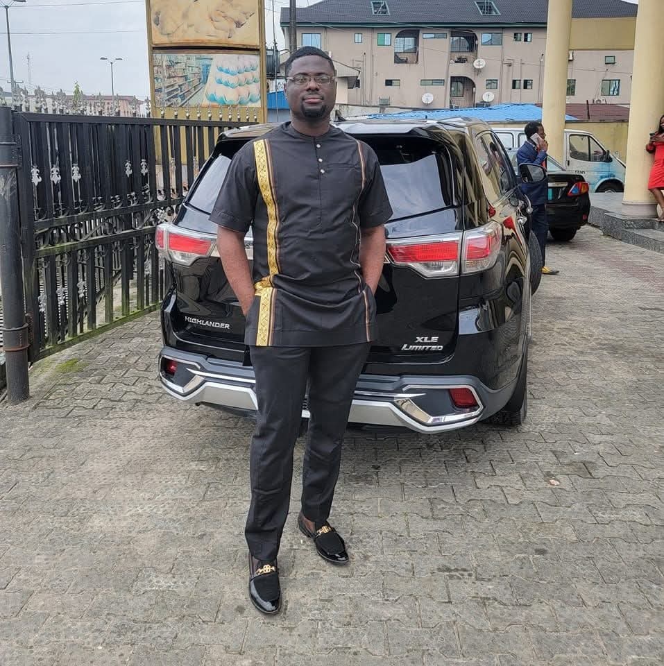 Uche Okochi standing in front of a black Toyota Highlander SUV